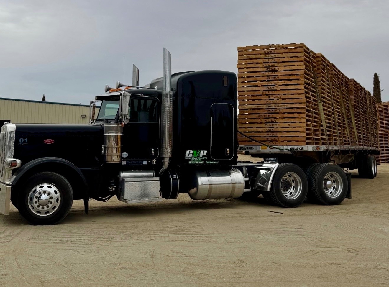 Black Green Valley Pallets truck beside a trailer stacked with pallets