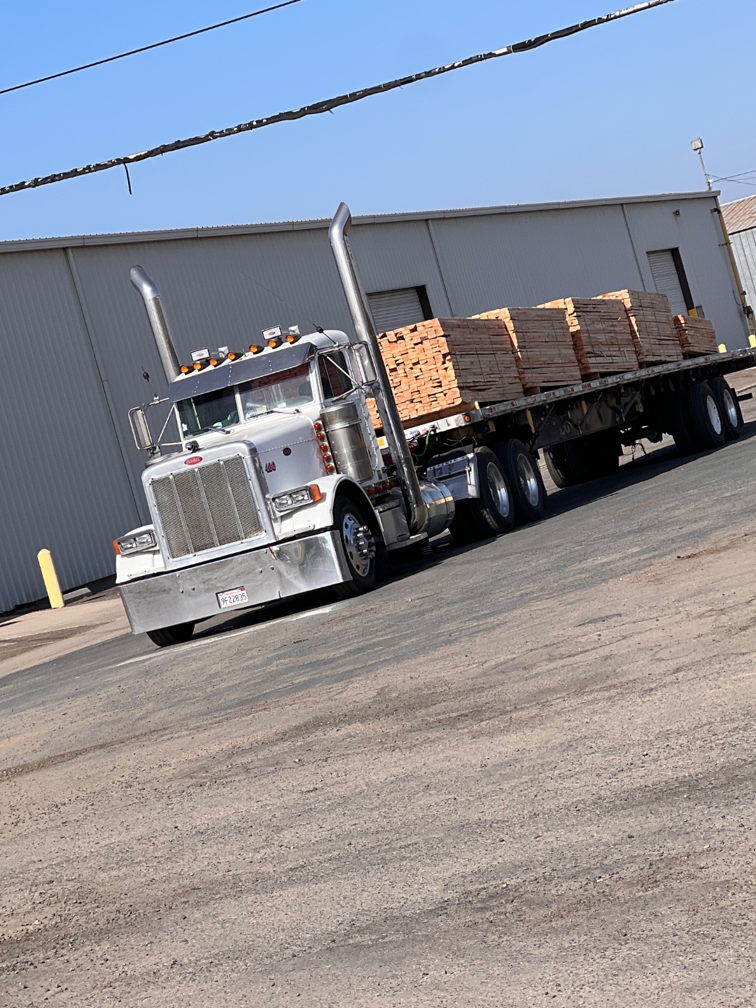 White Peterbilt with a flatbed trailer loaded with pallets