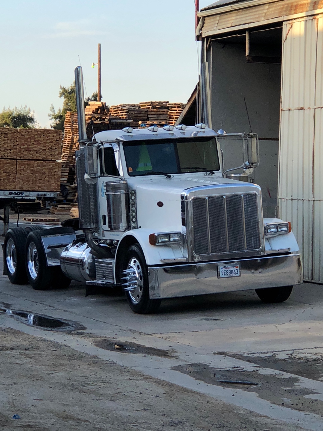 White Peterbilt truck parked at the Green Valley Pallets yard with pallets in the background